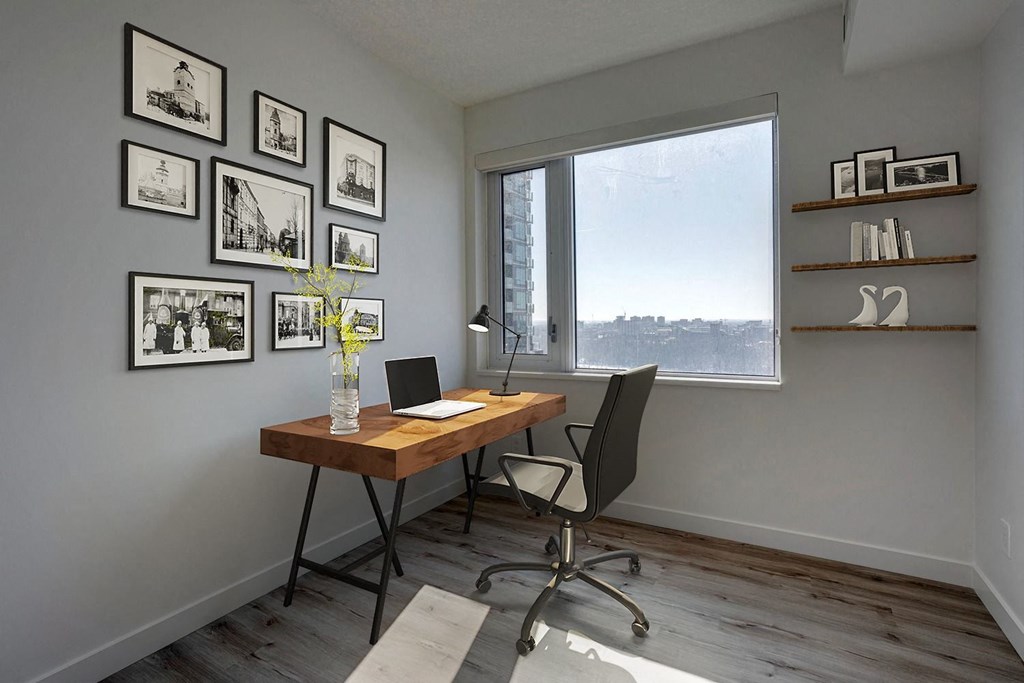 a desk with a laptop and a glass vase with flowers in a room with a large  at Citizen on Jasper, Edmonton, T5K 0M5