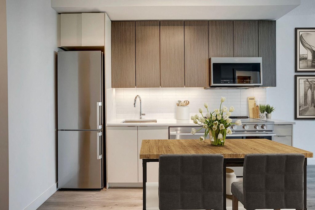 a kitchen with white cabinets and a wooden table  at Citizen on Jasper, Edmonton, AB, T5K 0M5