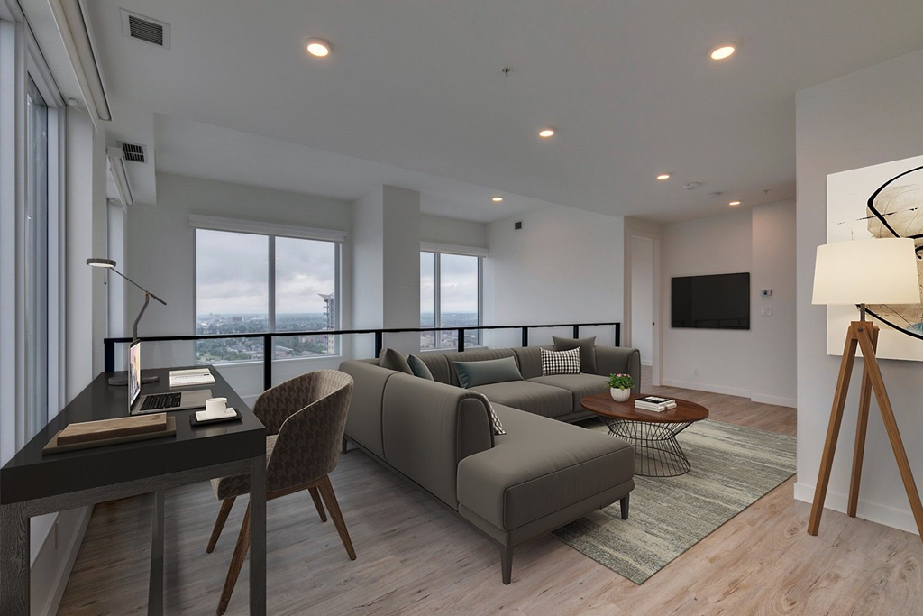a living room with a gray couch and a desk and a television at BLVD Beltline, Calgary, AB