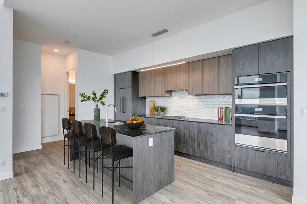 a modern kitchen with a large island with a counter top and chairs at BLVD Beltline, Calgary, AB