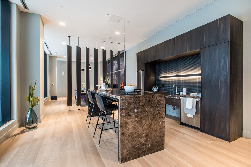 a large kitchen with a marble counter top and a bar with stools at The Village, Oakville