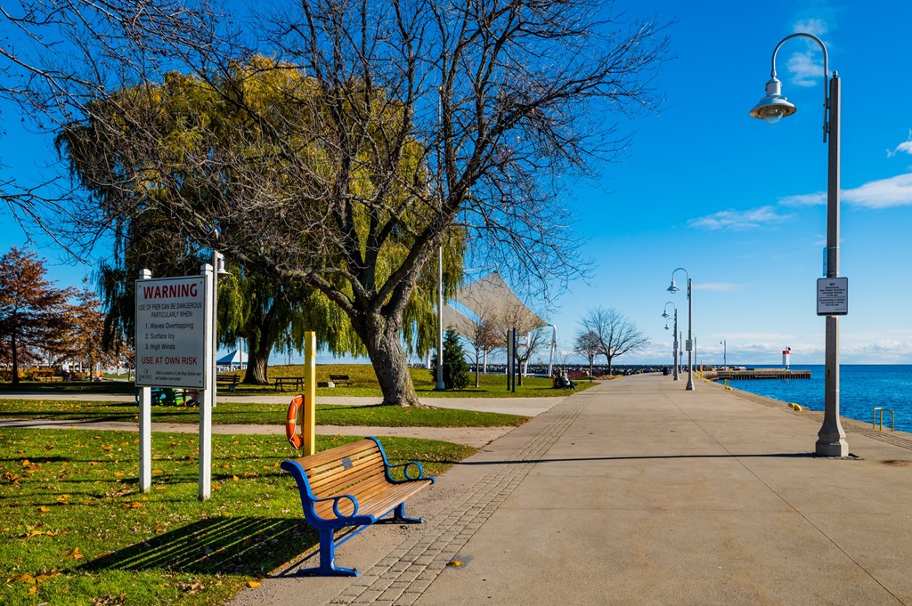 a park bench next to a sidewalk near the water