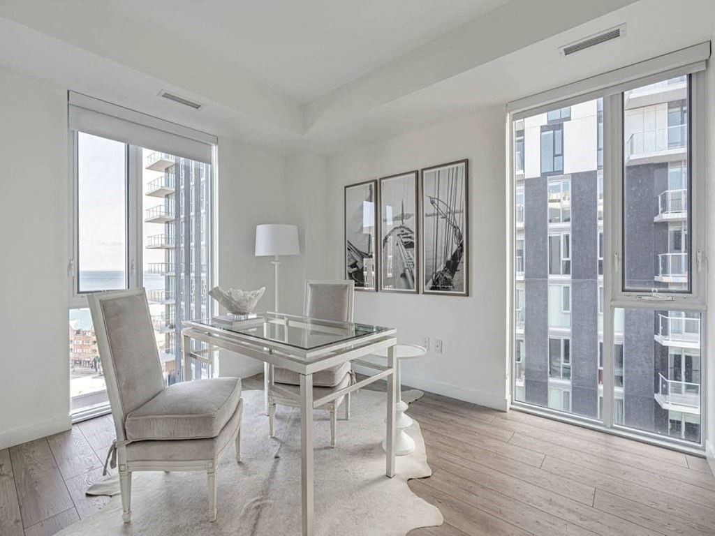 a living room with a glass desk and a large window  at The Village, Oakville, ON