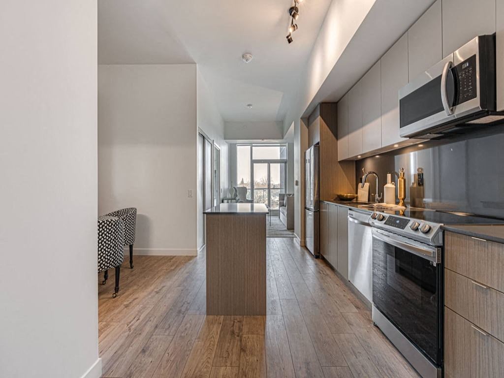 a kitchen and living room with a stove and a microwave at The Village, Oakville, ON