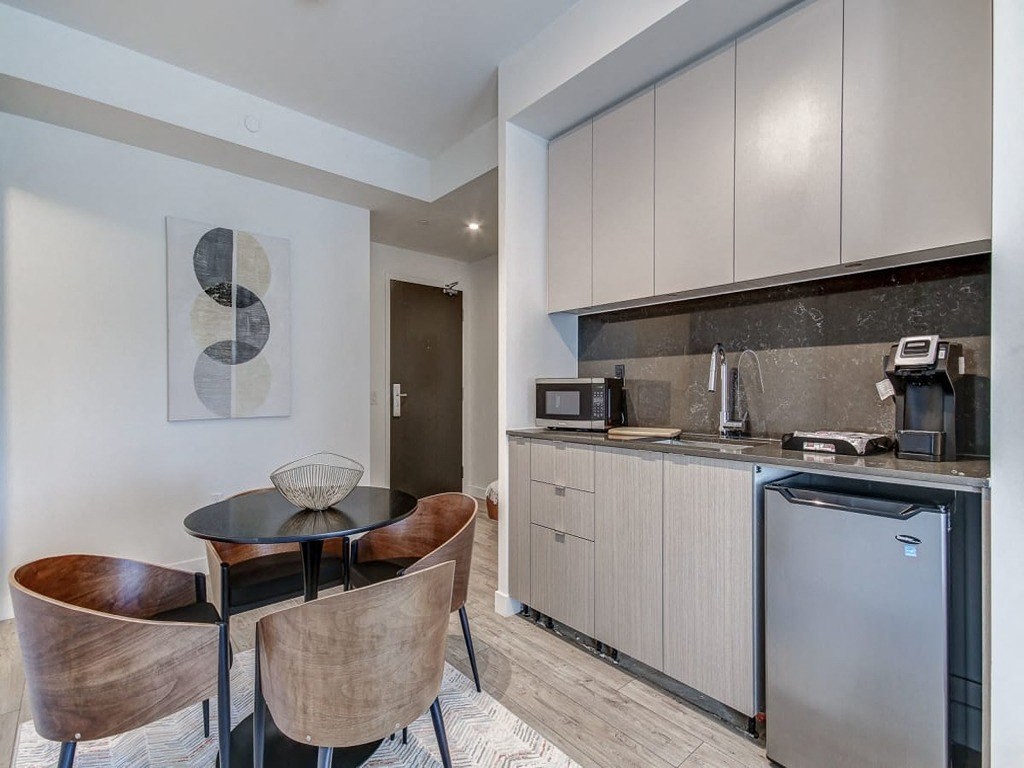 a kitchen and dining area with a small table and chairs at The Village, Oakville, ON