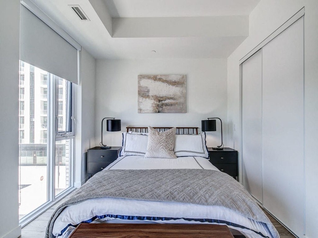 a bedroom with a bed and a large window  at The Village, Ontario