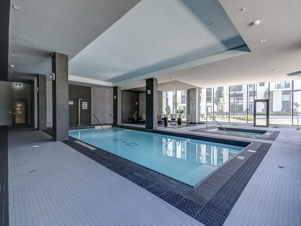 a swimming pool in a lobby of a building with a glass door at The Village, Ontario