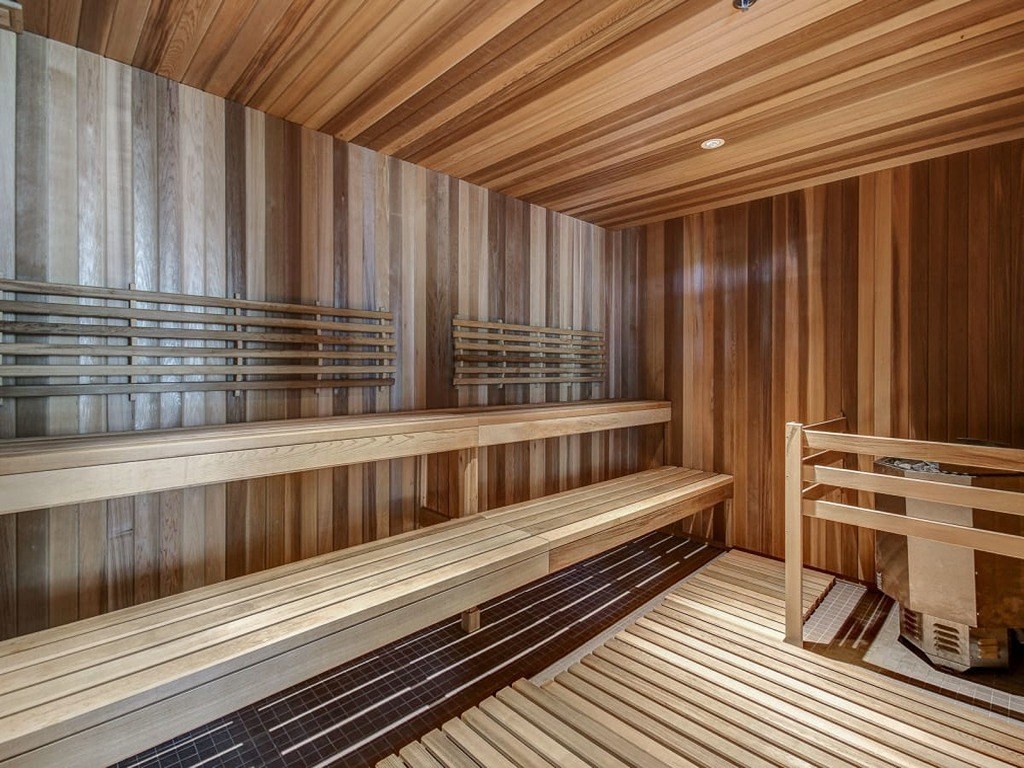 a wooden sauna with wooden benches and a chair at The Village, Oakville, ON