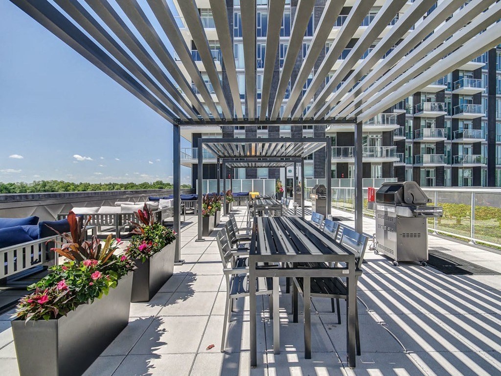 a roof deck with tables and chairs and a building in the background at The Village, Oakville, L6L 0H1