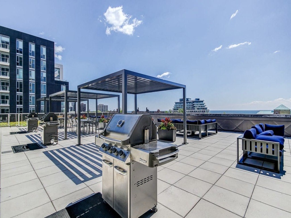 a barbecue grill on a roof with a city in the background at The Village, Oakville, ON