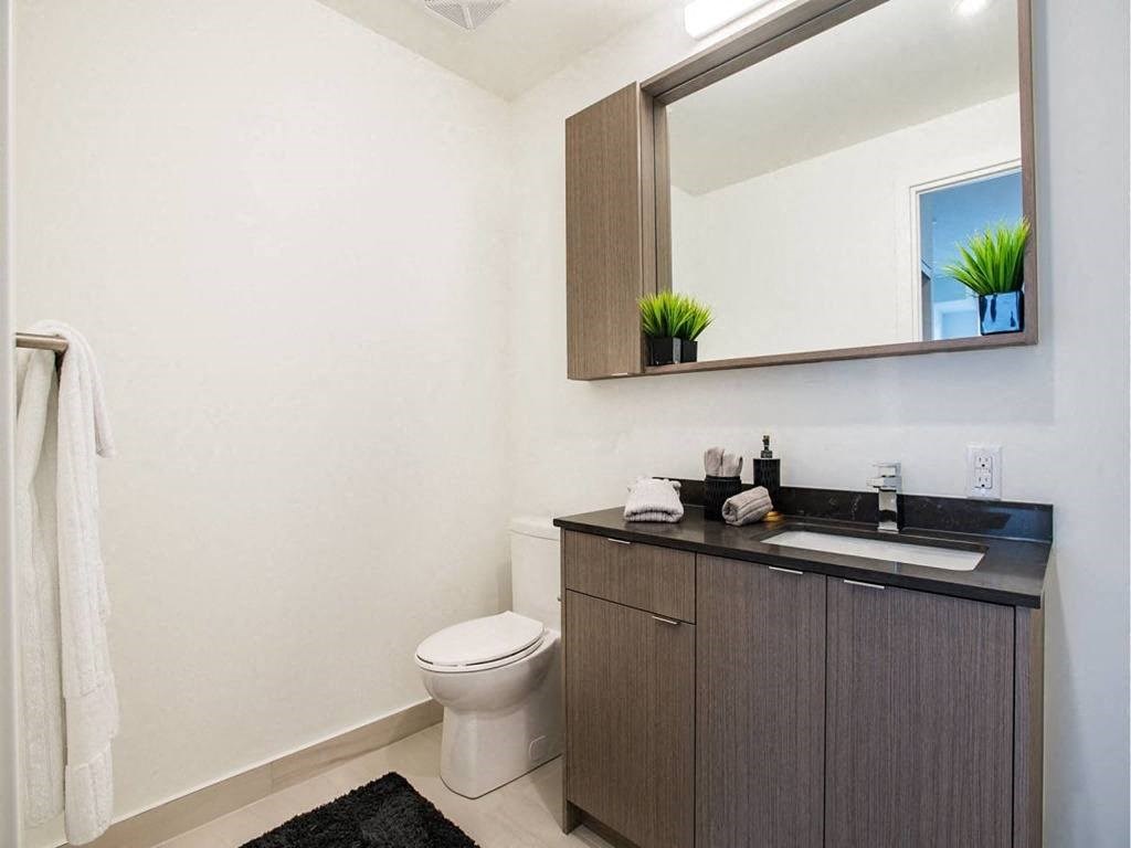 a bathroom with a toilet and a sink and a mirror  at The Village, Ontario