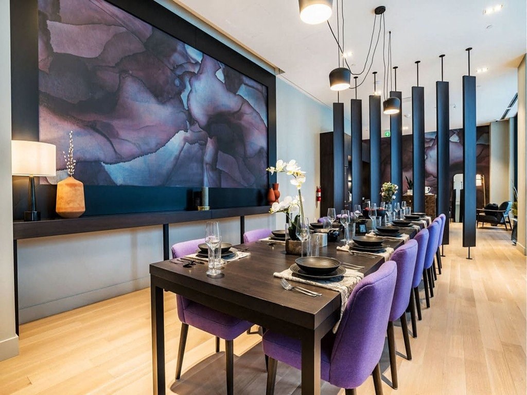 a dining room with a long table and purple chairs  at The Village, Oakville, ON