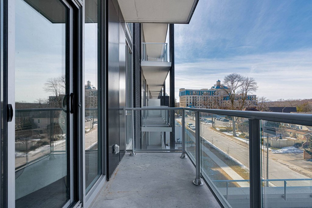 a balcony with glass doors and a view of a city