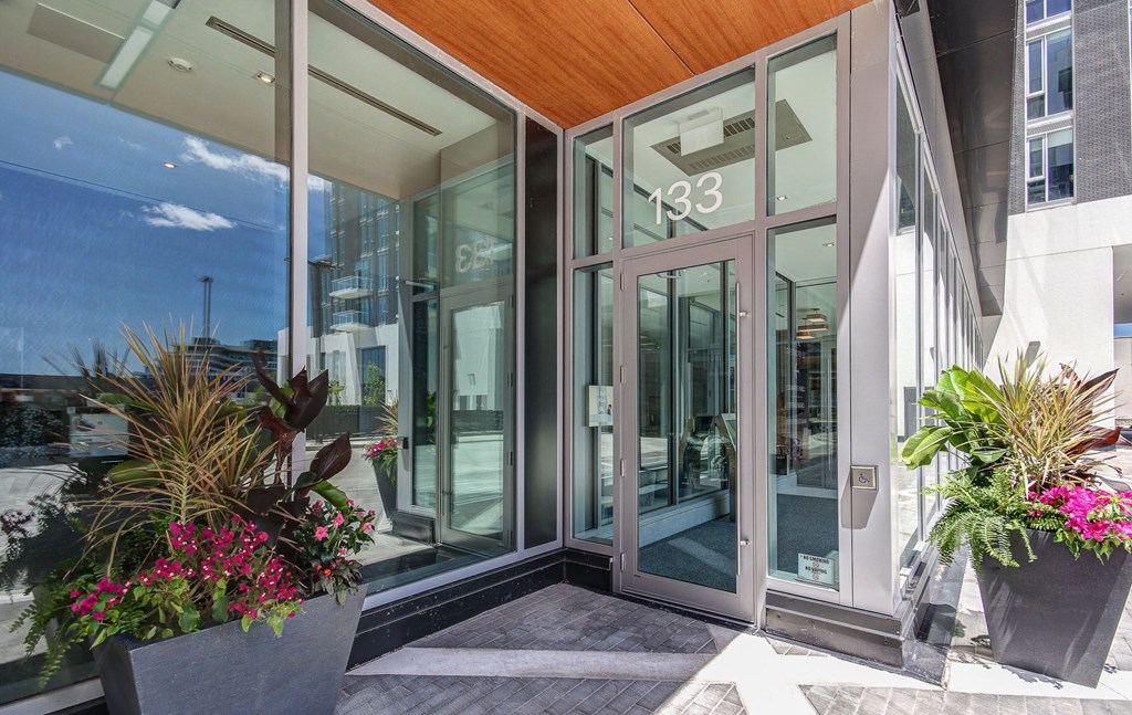 the entrance to a building with glass doors and flowers