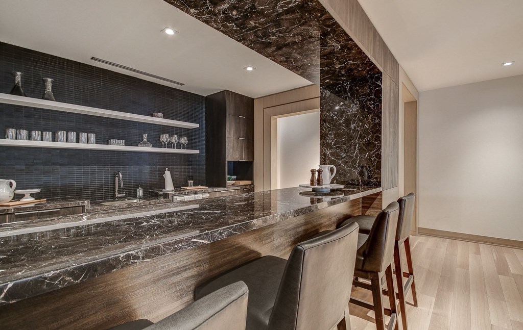 a kitchen with marble countertops and a long bar with chairs