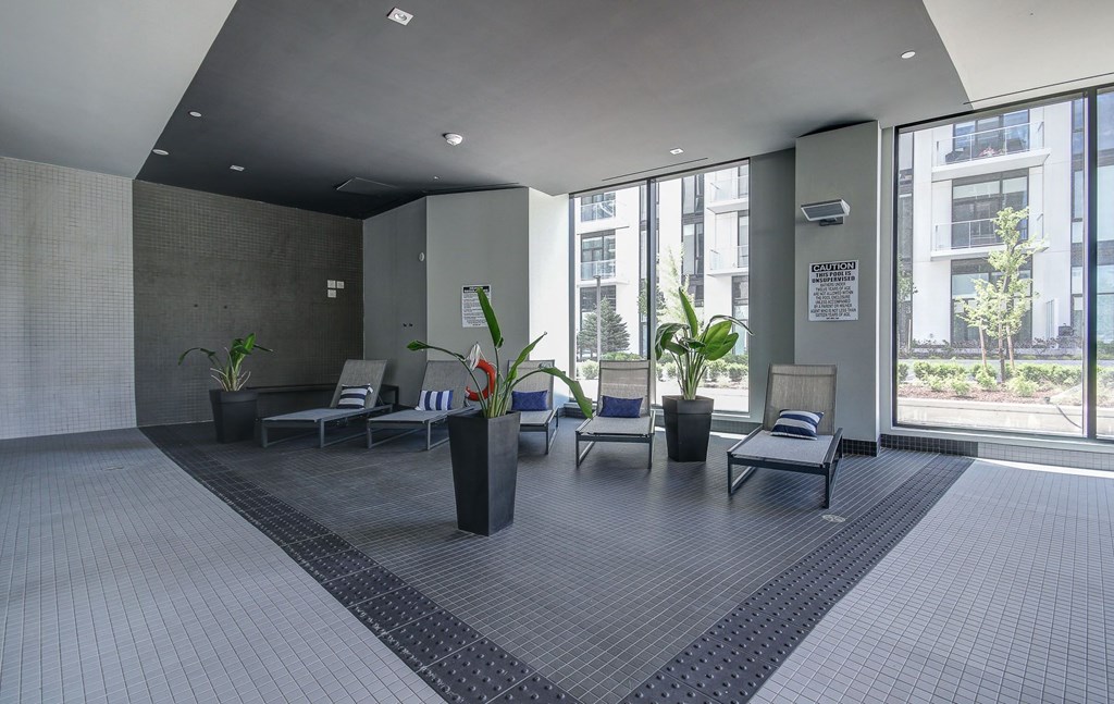 a large lobby with chairs and potted plants and large windows