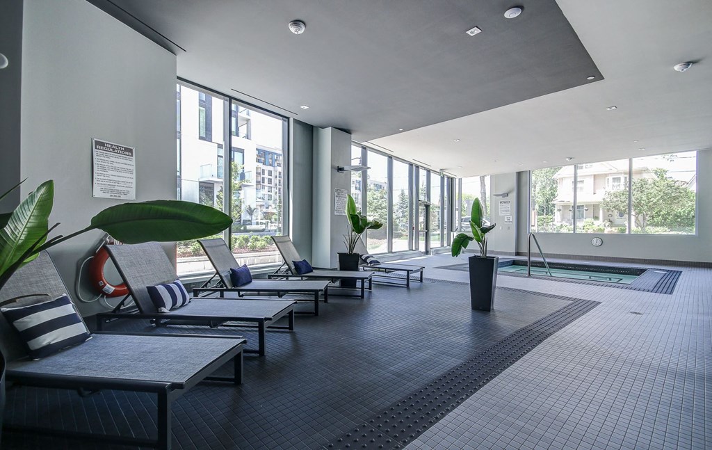 a lobby with lounge chairs and a pool in a building