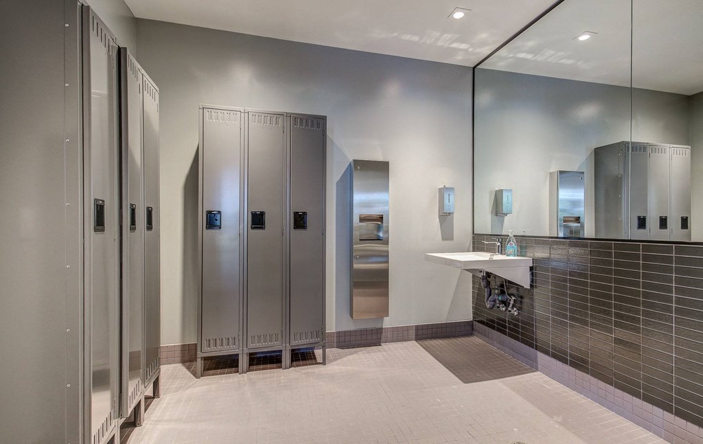 a large bathroom with stainless steel showers and a sink