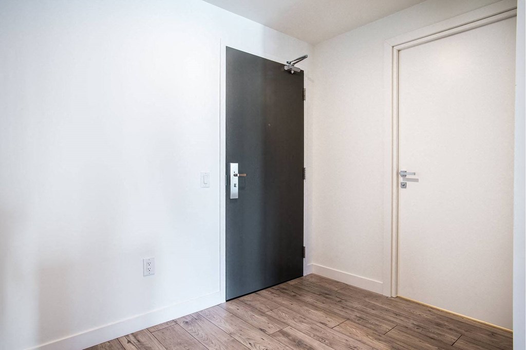 a black door in a room with white walls and wood floors