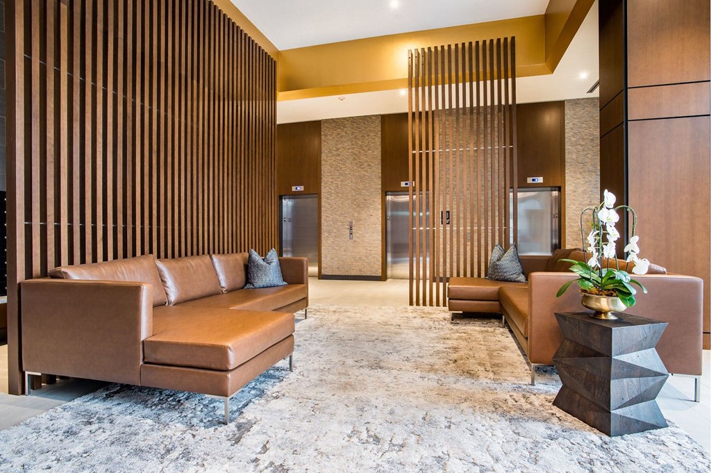 a lobby with brown couches and a white rug