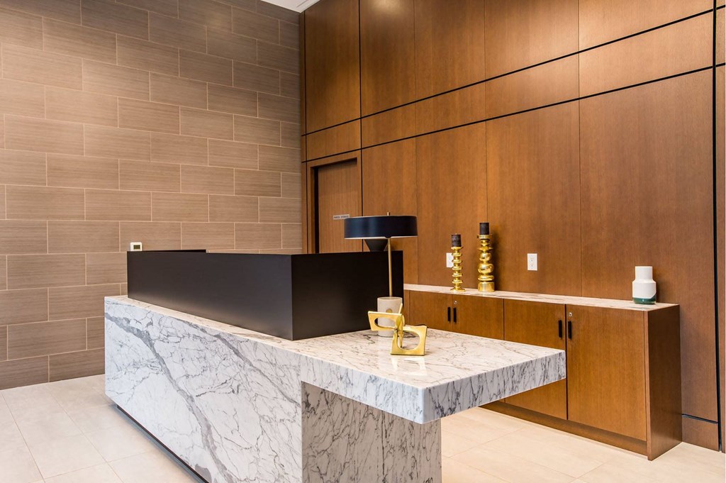 a reception desk in a hotel lobby with a marble desk top and wooden cabinets