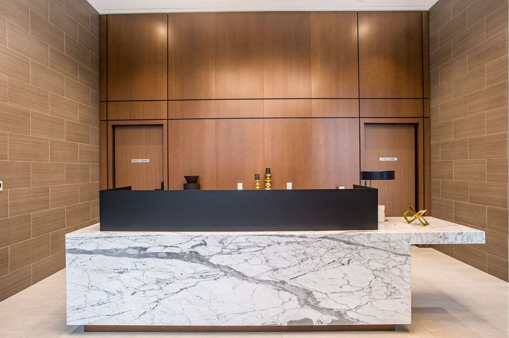 a reception desk in a hotel lobby with a granite desk top and wooden walls