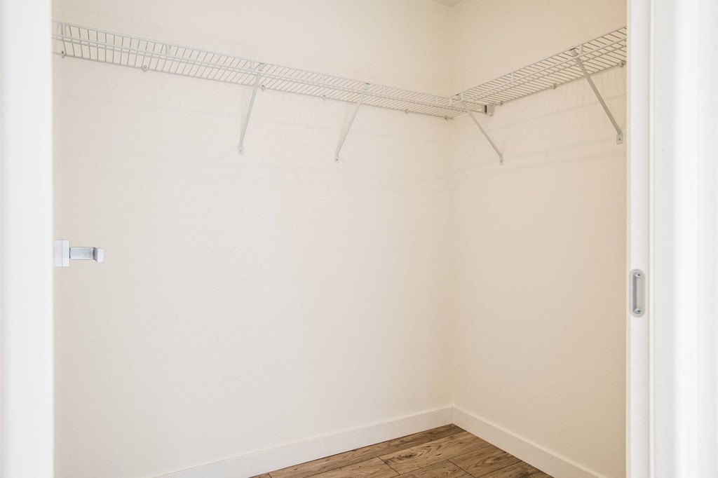 a white bathroom with a rack on the wall and a wood floor