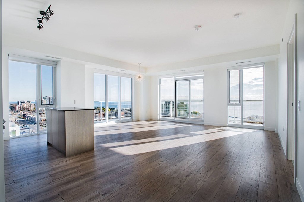 an empty living room with a desk and a view of the ocean
