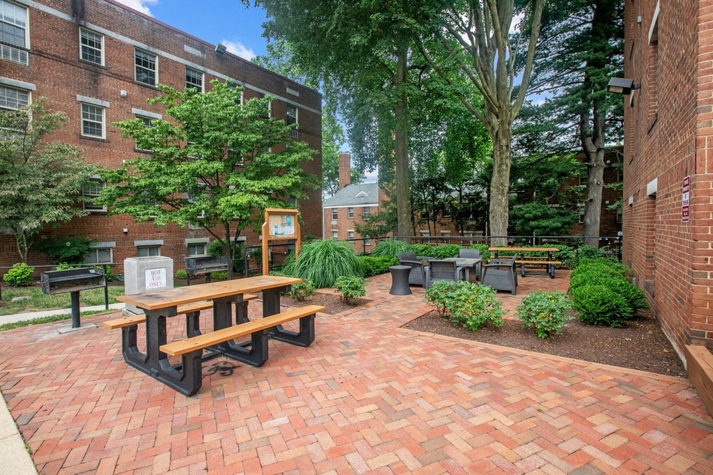 a brick patio with a picnic table and benches in front of a brick building