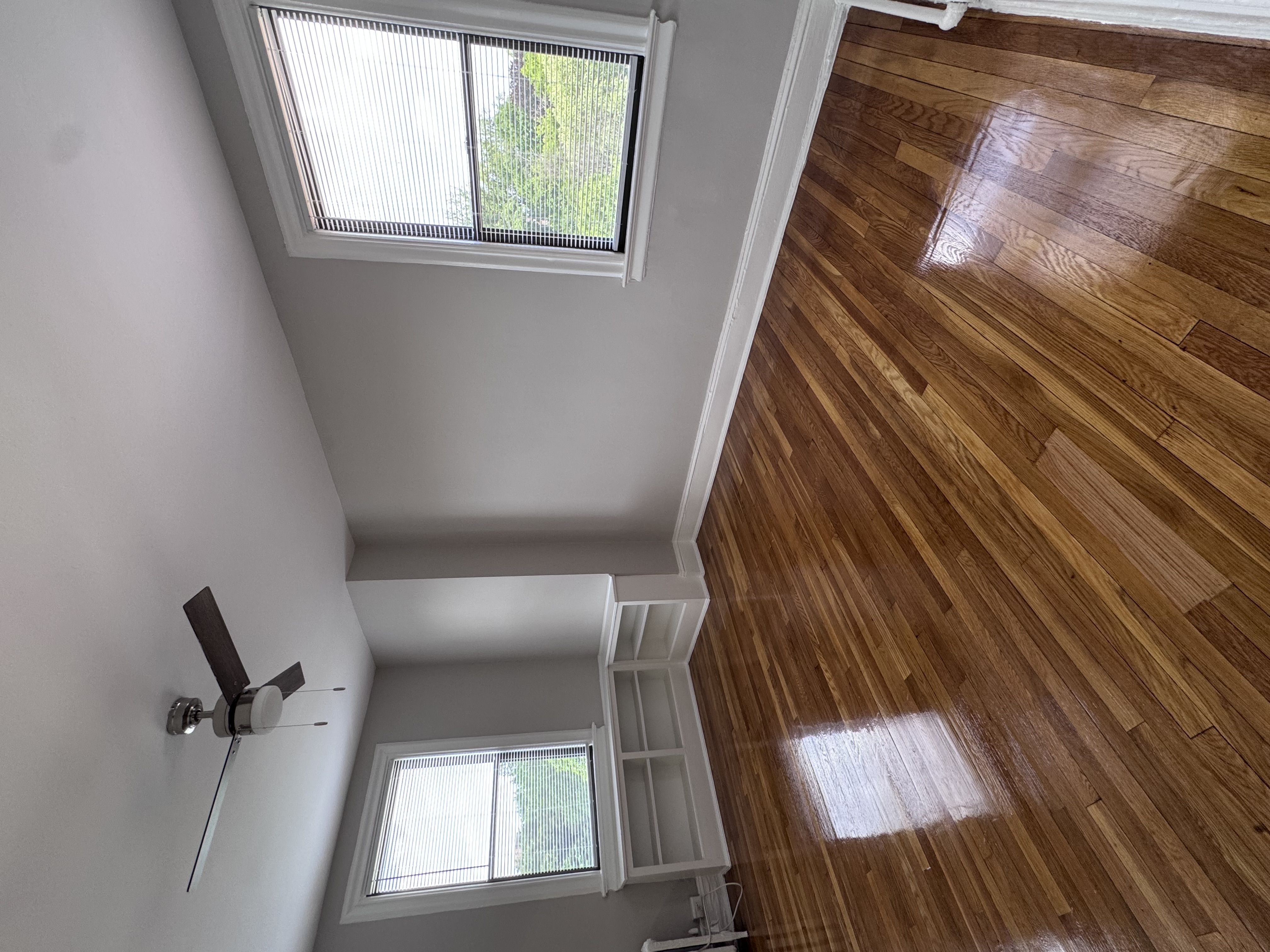 A room with a ceiling fan and wooden floors.