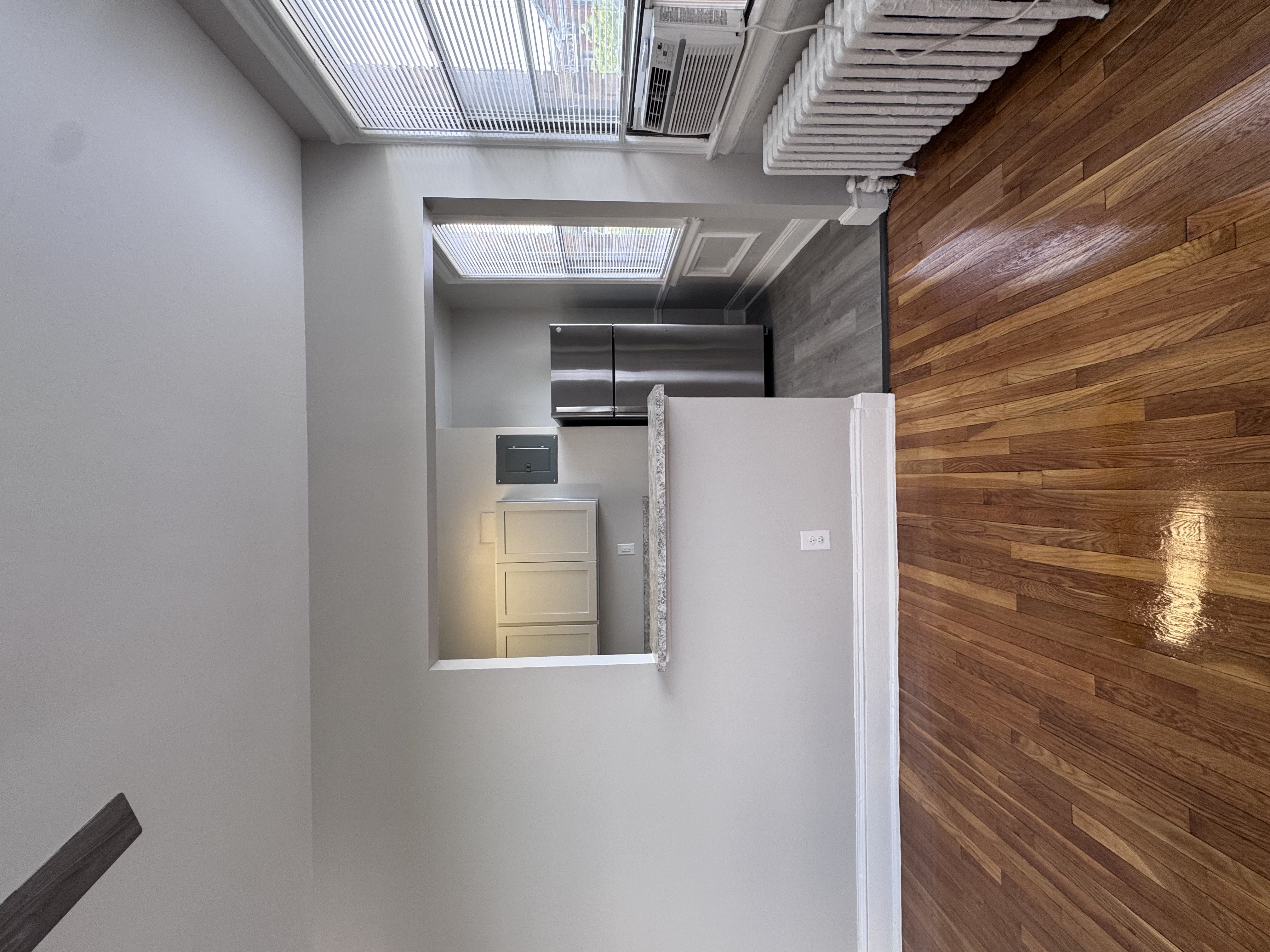 A room with a white wall and a wooden floor.