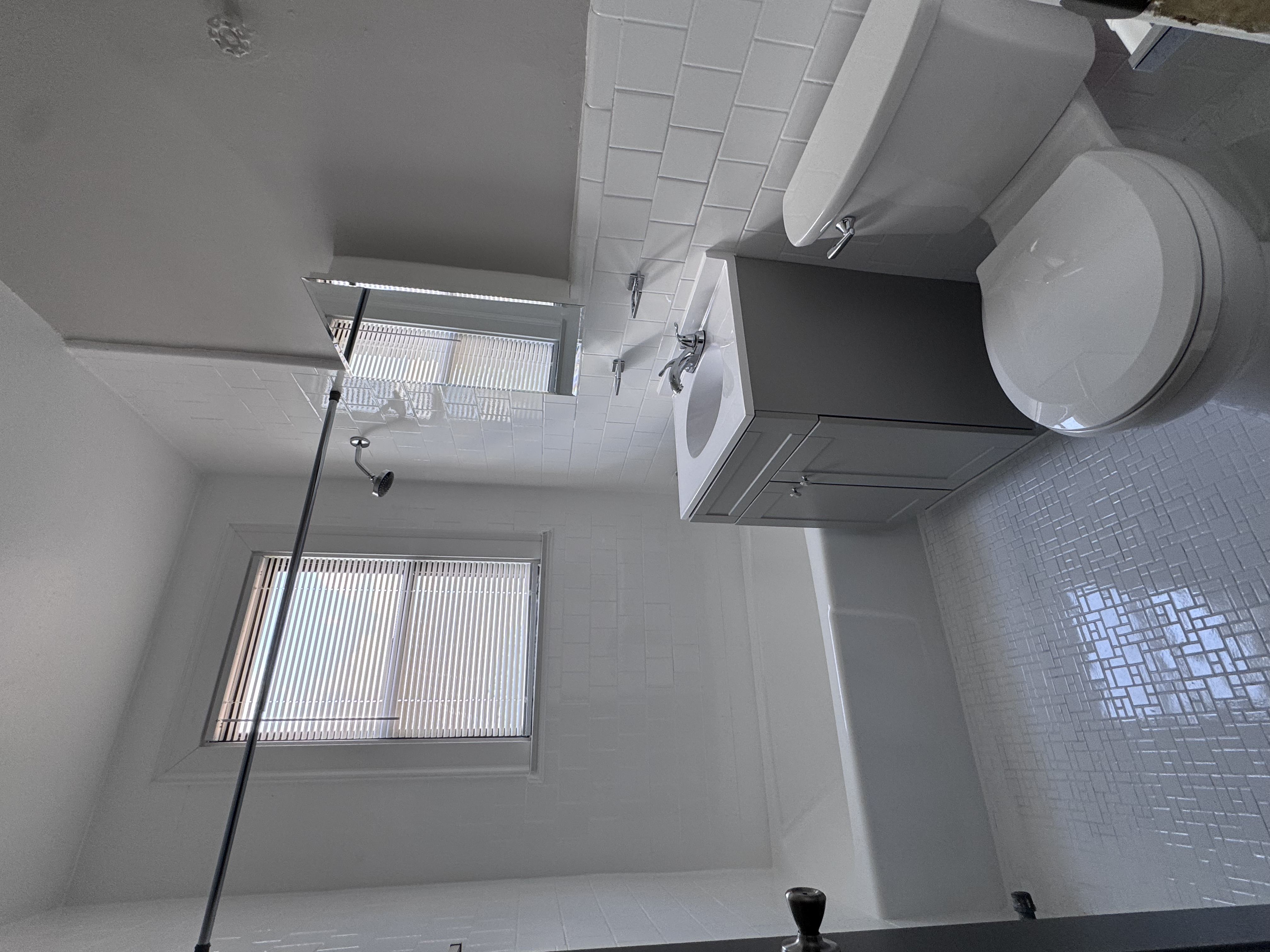 A bathroom with a toilet, sink, and a window.