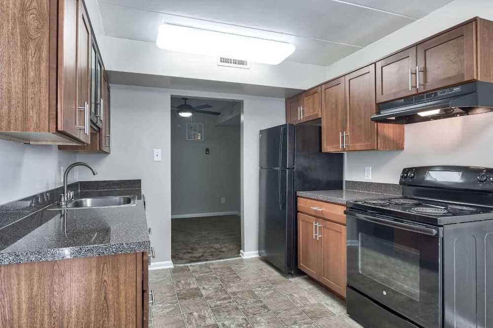 an empty kitchen with black appliances and wooden cabinets