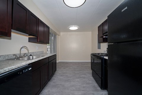 A kitchen with black appliances and brown cabinets.