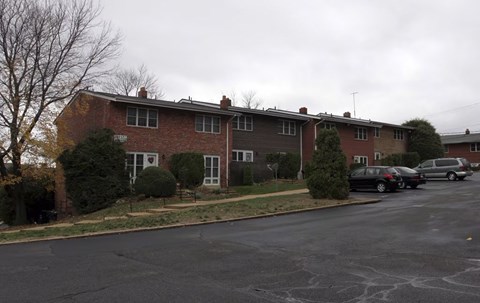 A brick apartment building with a parking lot in front.