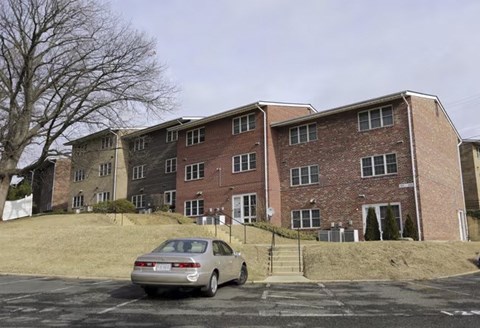 A car is parked in front of a brick apartment building.
