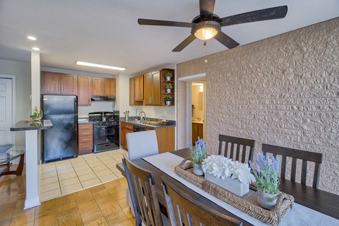 a dining room and kitchen with a table and a ceiling fan