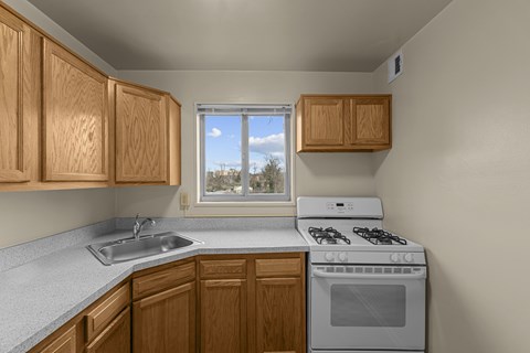 A kitchen with wooden cabinets and a white stove top oven.at Kensington House, Kensington, MD