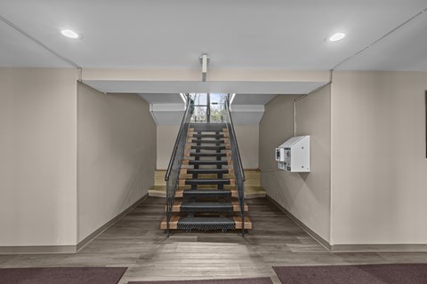 A staircase with a metal railing leads up to a bright area.at Kensington House, Kensington Maryland