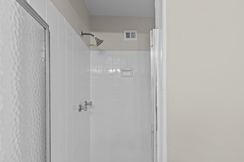 A white tiled shower with a silver faucet.at Kensington House, Kensington