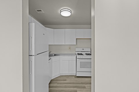 A white kitchen with a refrigerator, oven, and cabinets.at Kensington House, Kensington, MD 20895