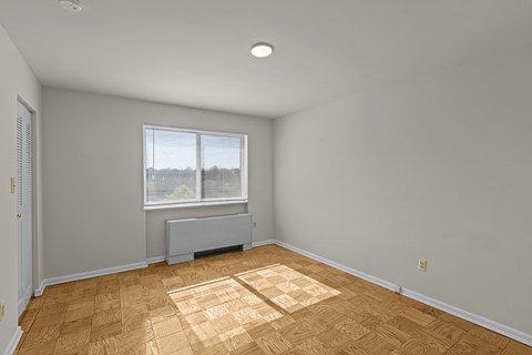 A room with wooden flooring and a window with blinds.at Kensington House, Kensington, MD 20895
