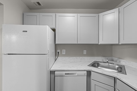 A white refrigerator is in a kitchen with a white counter top.