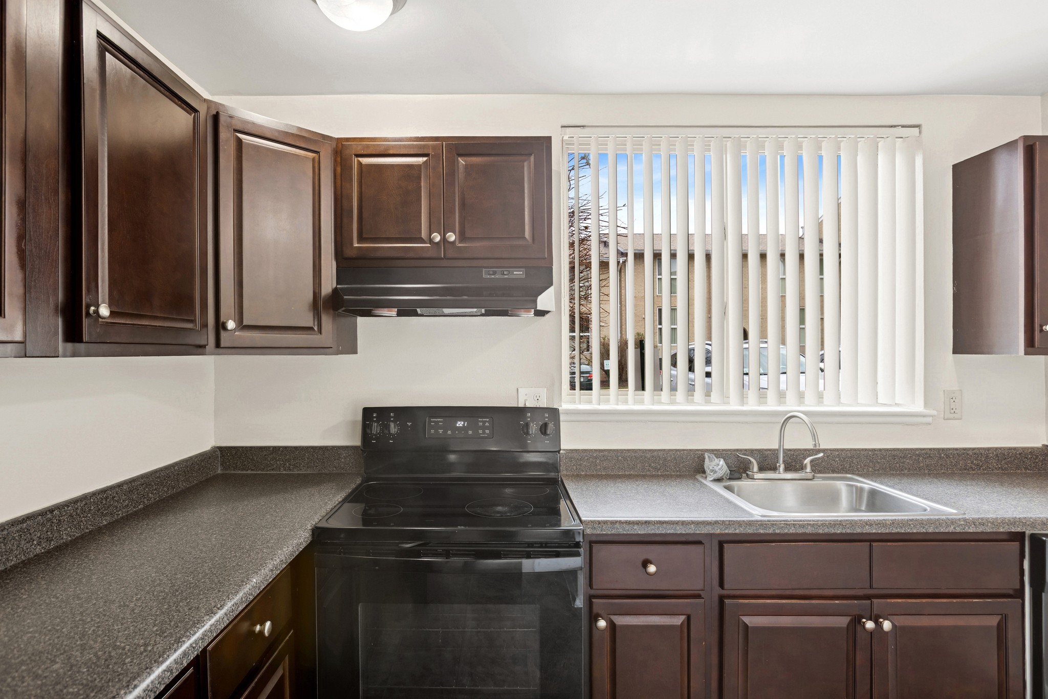 A kitchen with dark brown cabinets and a black stove top oven.