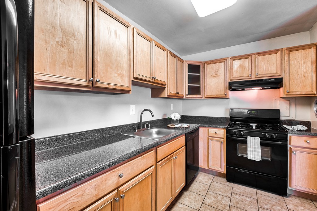 full kitchen with black appliances and granite counter tops and wood cabinets