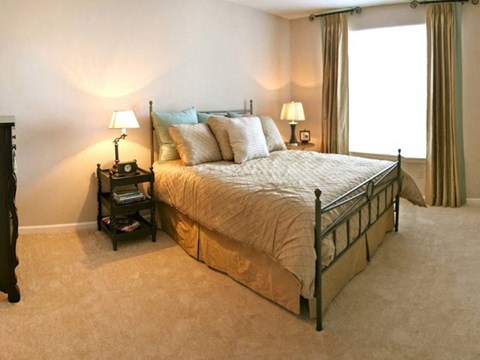 A bedroom with a large bed and two lamps on either side of the bed.