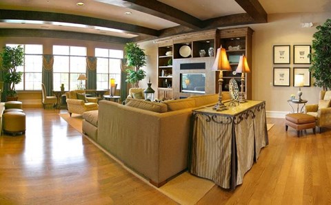 A living room with a long couch and a table with a lamp on it.