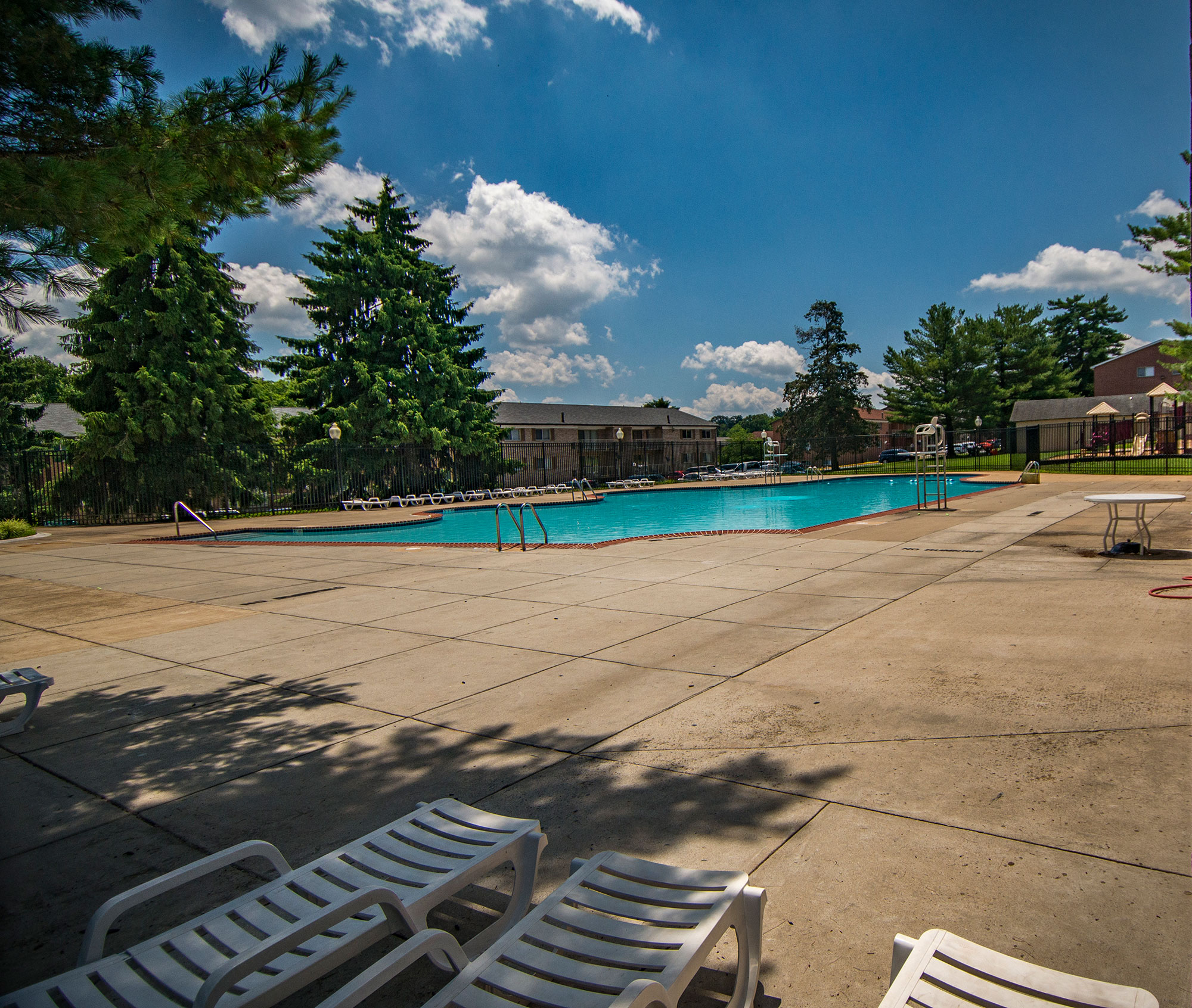 a swimming pool with chairs around it and trees