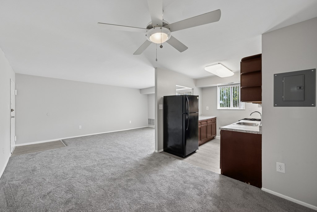 A spacious kitchen with a black refrigerator and a ceiling fan.