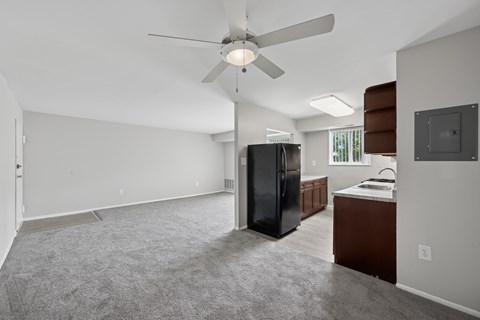 A spacious kitchen with a black refrigerator and a ceiling fan.